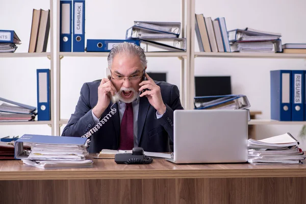 Old male employee unhappy with excessive work — Stock Photo, Image