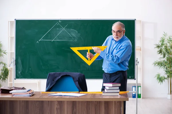 Velho professor de geometria masculina segurando triângulo — Fotografia de Stock