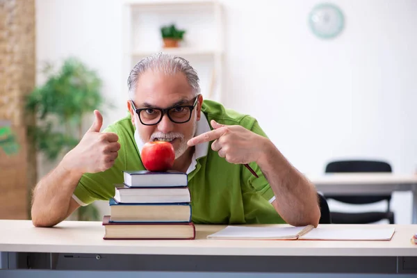 Старый студент ест яблоко во время подготовки к экзамену — стоковое фото