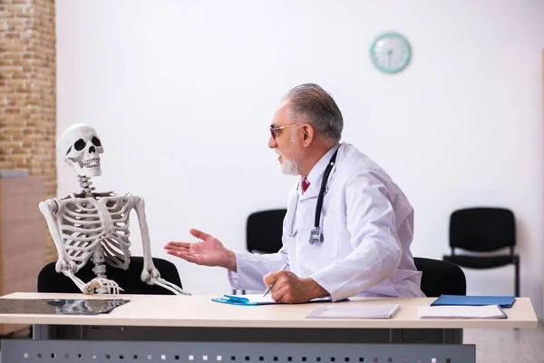 Oude mannelijke dokter en skelet patiënt in de kliniek — Stockfoto