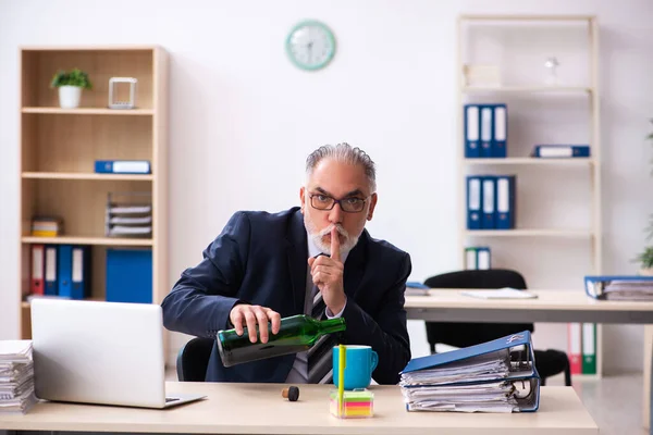 Un vieil employé boit de l'alcool au bureau — Photo