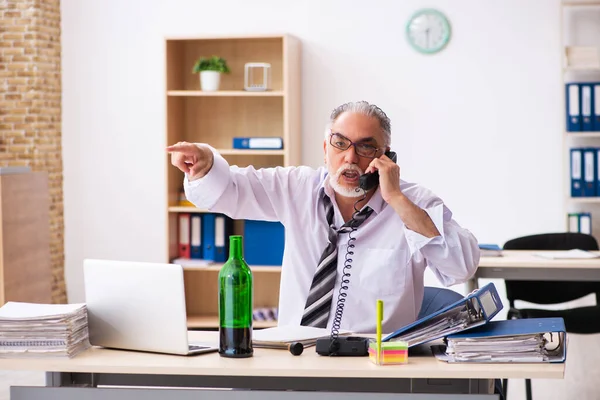 Un vieil employé boit de l'alcool au bureau — Photo