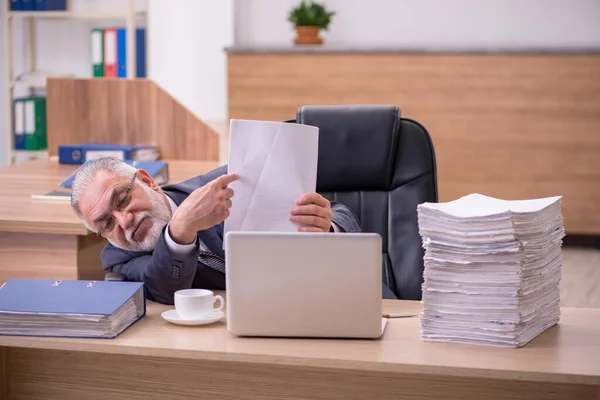Oude mannelijke werknemer leest papier in het kantoor — Stockfoto