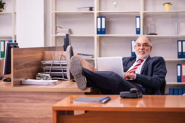 Oude mannelijke werknemer zit in het kantoor — Stockfoto