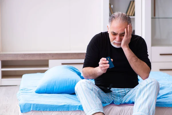 Oude man loopt zonder geld in de slaapkamer — Stockfoto