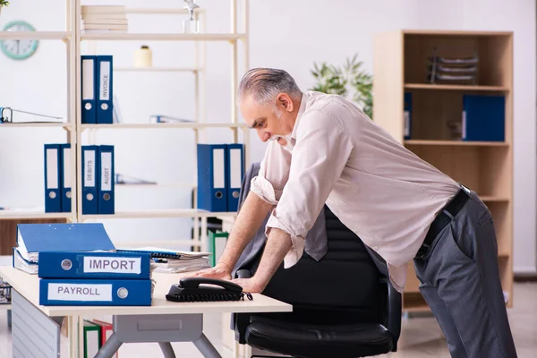 Velho funcionário do sexo masculino fazendo exercícios físicos no local de trabalho — Fotografia de Stock