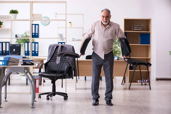 Oude mannelijke werknemer doet fysieke oefeningen op de werkplek — Stockfoto