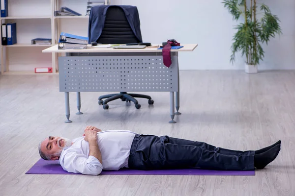 Empleado varón envejecido haciendo ejercicios físicos durante el descanso — Foto de Stock