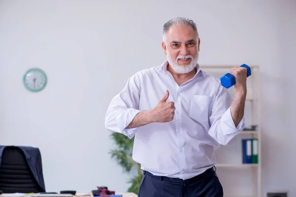 Verouderde mannelijke werknemer doet fysieke oefeningen tijdens de pauze — Stockfoto