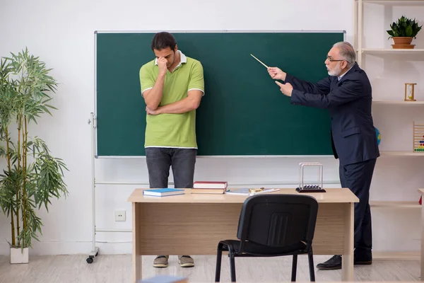Aged teacher and male lazy student in the classroom