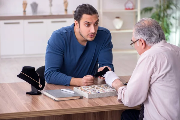 Joven visitando viejo joyero masculino — Foto de Stock