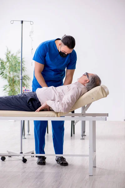 Old patient visiting young male doctor for intravenous therapy — Stock Photo, Image