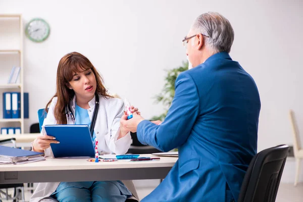 Velho empresário visitando jovem médico feminino — Fotografia de Stock