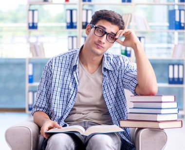 Öğrenci kitap okuyor ve kütüphanede sınavlara hazırlanıyor