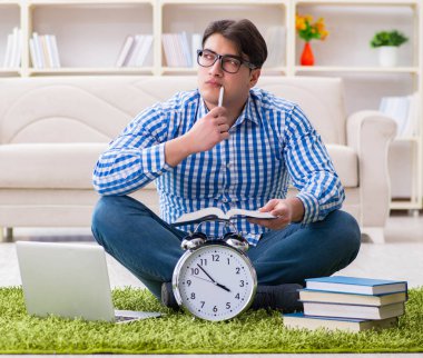 Genç yakışıklı adam evde yerde oturuyor.