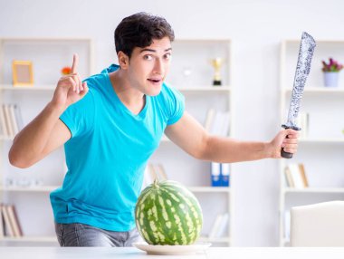 Evde karpuz yiyen bir adam.