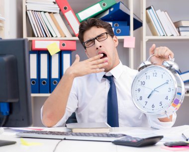 Ofiste kitap ve kağıtlarla çalışan bir işadamı.