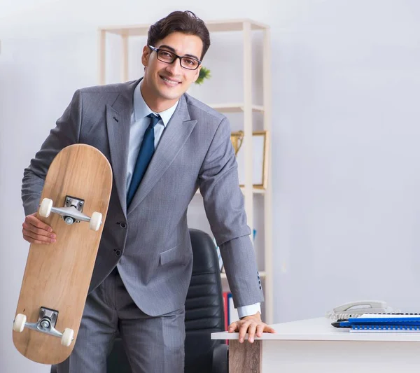 Jovem empresário andando de skate no escritório durante o intervalo — Fotografia de Stock