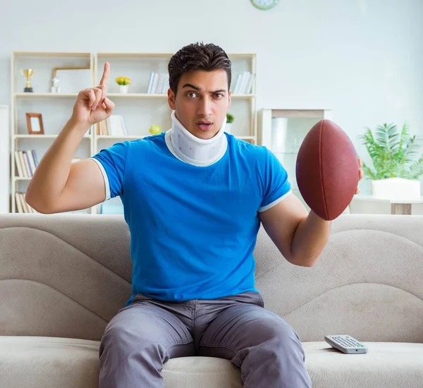 Homem com lesão no pescoço assistindo futebol americano em casa — Fotografia de Stock