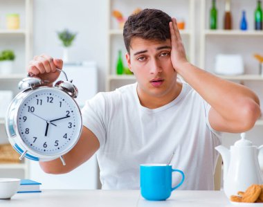 Çalar saati olan bir adam kahvaltıda uyuyakalıyor.