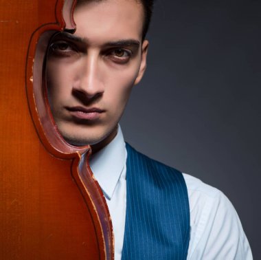 Genç adam karanlık odada çello çalıyor.