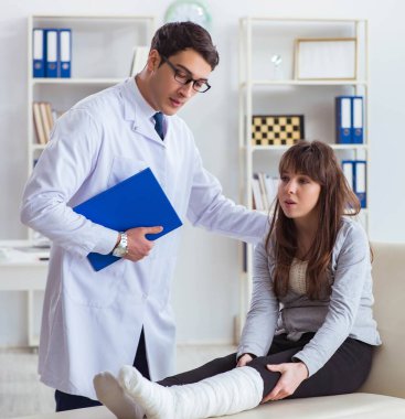 Kırık bacaklı bir hastayı muayene eden doktor.