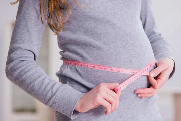 Gravid kvinna som mäter magen med centimeter — Stockfoto