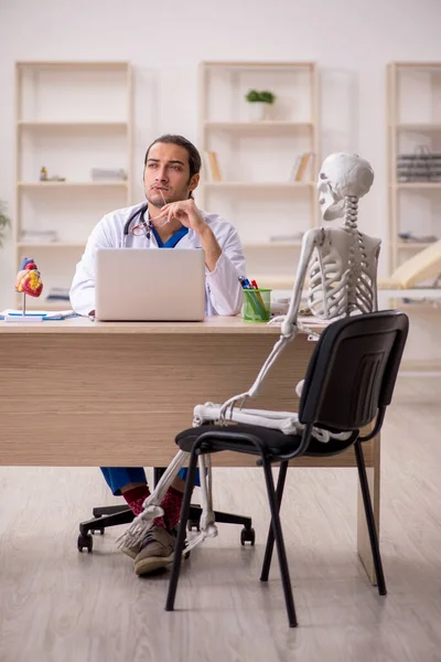 Klinikteki genç erkek doktor ve iskelet hastası. — Stok fotoğraf