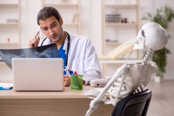 Jonge mannelijke arts radioloog en skelet patiënt in de kliniek — Stockfoto