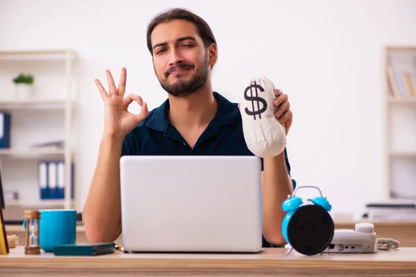 Młody mężczyzna pracownik trzyma torbę z pieniędzmi w biurze — Zdjęcie stockowe