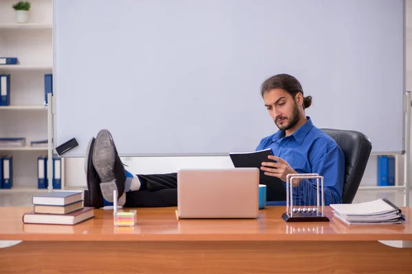 Jonge mannelijke leraar natuurkundige zittend in de klas — Stockfoto