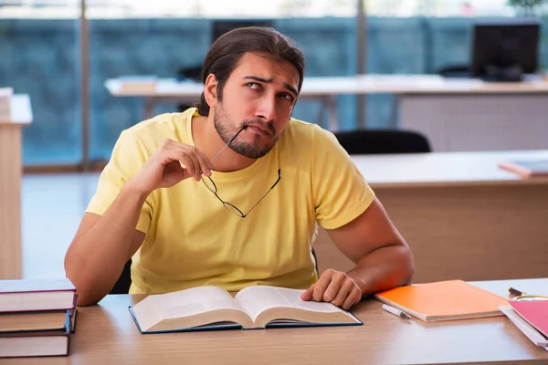 Ung manlig student förbereder sig för tentor i klassrummet — Stockfoto