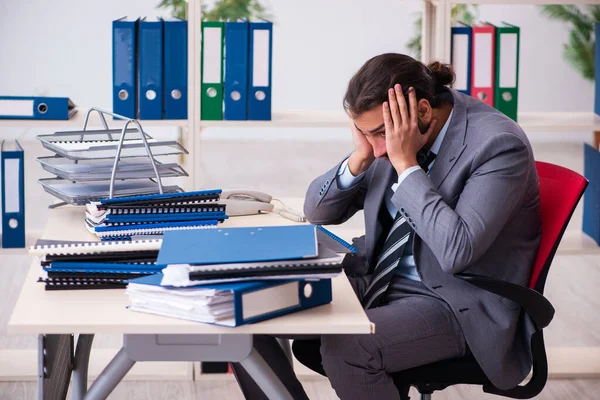 Jonge mannelijke werknemer ongelukkig met overmatig werk in het kantoor — Stockfoto