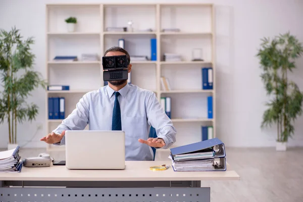 Jonge mannelijke werknemer met een virtuele bril op de werkplek — Stockfoto