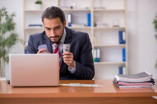 Young male employee playing cards at workplace