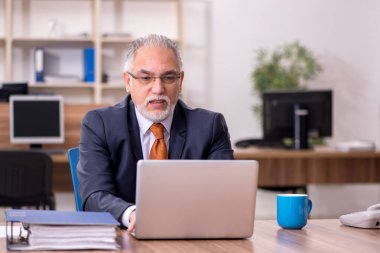 Ofiste çalışan yaşlı bir erkek.