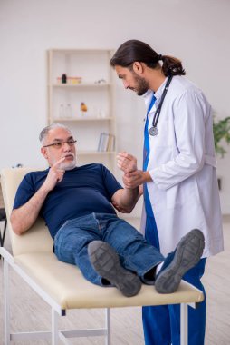 Yaşlı erkek hasta, genç erkek doktor masörünü ziyaret ediyor.