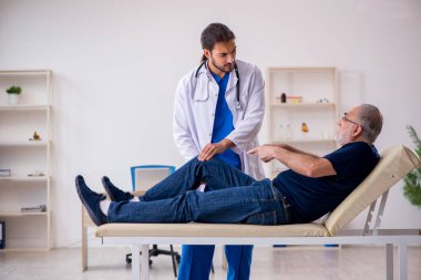 Yaşlı erkek hasta, genç erkek doktor masörünü ziyaret ediyor.