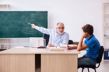 Yaşlı erkek öğretmen ve okul çocuğu sınıfta.
