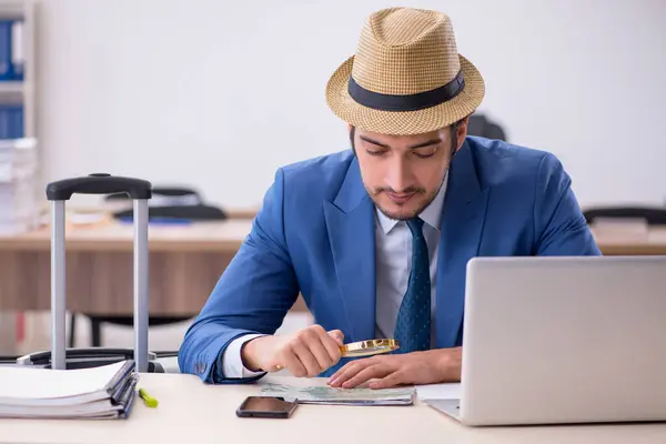 Young male employee preparing for trip in the office