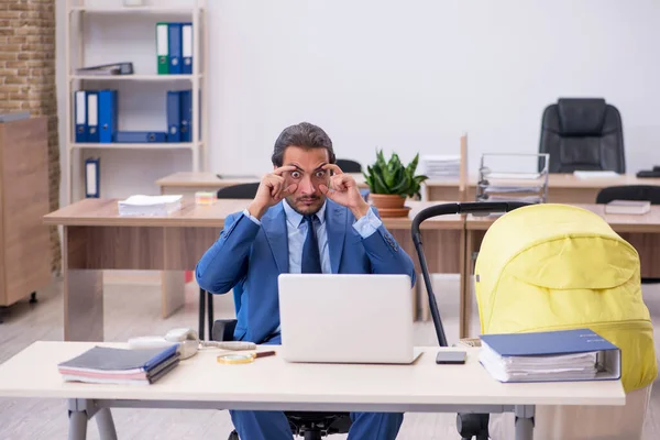 Ung manlig anställd som tar hand om nyfödda på arbetsplatsen — Stockfoto