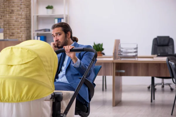 Joven empleado masculino que cuida a recién nacido en el lugar de trabajo — Foto de Stock