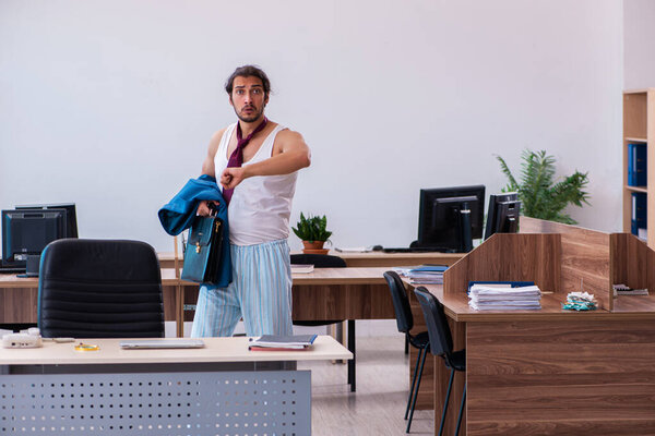 Young male employee coming to work straight from bed