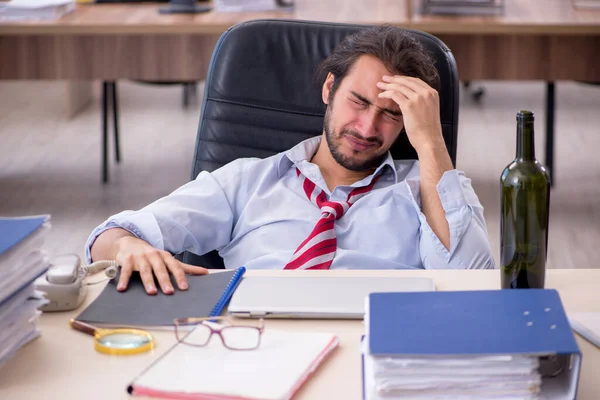 Jonge mannelijke werknemer drinkt alcohol op kantoor — Stockfoto