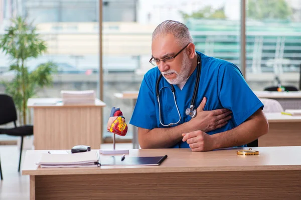 Viejo médico cardiólogo que trabaja en la clínica — Foto de Stock