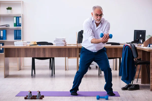 Velho empresário empregado fazendo exercícios esportivos no escritório — Fotografia de Stock