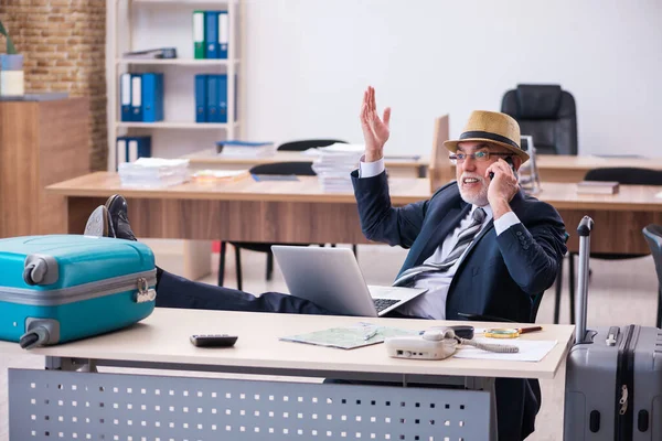 Old male employee preparing for travel in the office — Stock Photo, Image