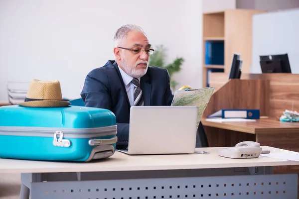 Oude mannelijke werknemer bereidt zich voor op reizen in het kantoor — Stockfoto