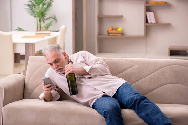 Vieil homme buvant de l'alcool à la maison — Photo