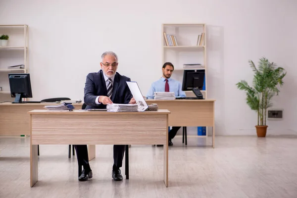 Velho chefe masculino e jovem empregado que trabalha no escritório — Fotografia de Stock